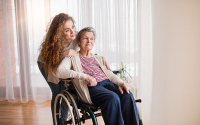 Enkelin zu Hause bei Ihrer Großmutter im Rollstuhl Eine Enkelin kümmert sich um Ihre Großmutter